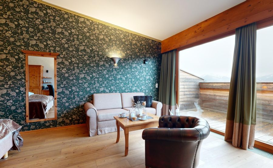 Romantisk suite med siddeområde med sofa og lænestol med udsigt over balkonen